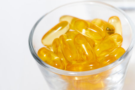 dietary supplement - fish oil capsules in a glass, top view closeup