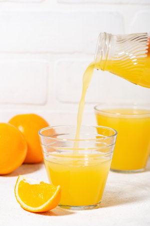 freshly squeezed orange juice is poured into a glass, closeup verticalの写真素材
