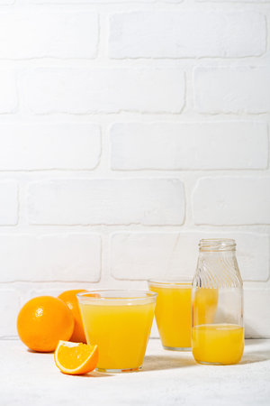glasses of freshly squeezed orange juice on a white background, vertical closeupの写真素材