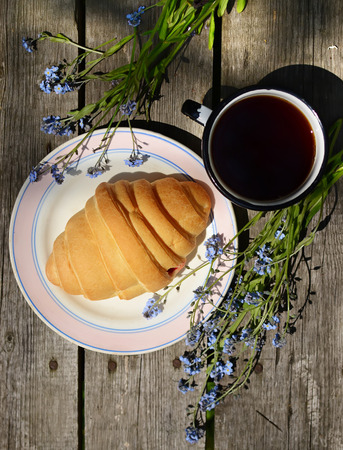 croissants and tea on old wooden table の写真素材
