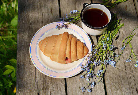 croissants and tea on old wooden table の写真素材