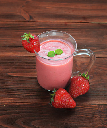 Glass of strawberry smoothie on a wooden backgroundの写真素材