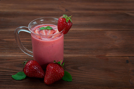 Glass of strawberry smoothie on a wooden backgroundの写真素材