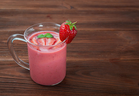 Glass of strawberry smoothie on a wooden backgroundの写真素材
