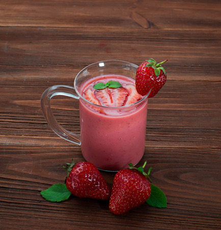 Glass of strawberry smoothie on a wooden backgroundの写真素材