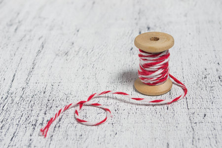 Christmas decorative red and white thread in light wooden background. Space for text