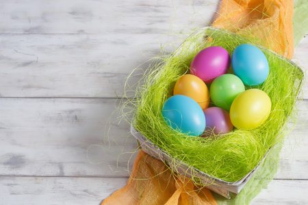 Basket with colored Easter eggs in light background. Space for text