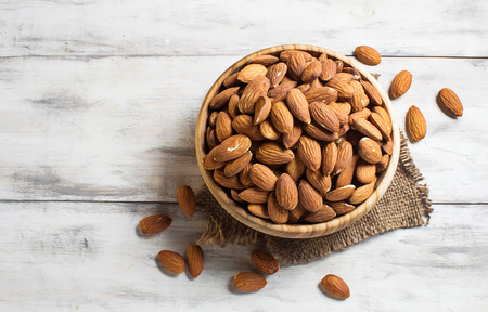 Almonds in brown bowl on wooden backgroundの写真素材