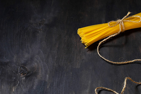 Uncooked spaghetti on dark background. Selective focus. Copy space backgroundの写真素材