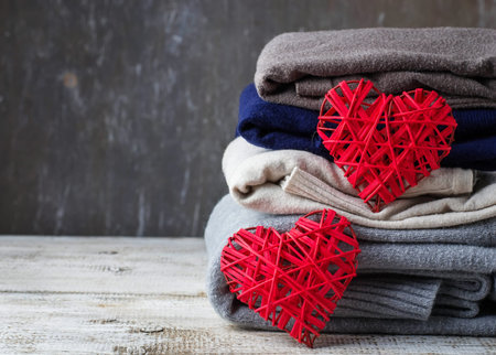 Stack of warm knitted clothes, sweaters and heart. Selective focus