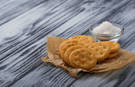 Salty cracker and salt on wooden background. Selective focus