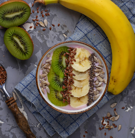 Smoothie in bowl with banana, kiwi, chia, flax and sunflower seeds. Selective focusの写真素材