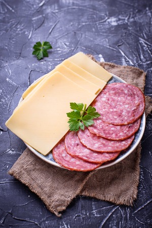 Sliced cheese and salami on plate. Selective focusの写真素材