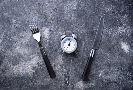 Grey alarm clock with knife and forkの写真素材