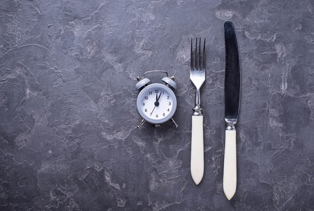 Grey alarm clock with knife and fork. Top viewの写真素材