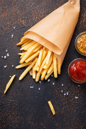 French fries in a paper bag with sauces. Top view