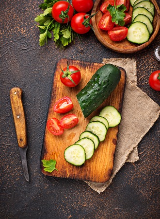 Sliced tomato and cucumber on cutting boardの写真素材