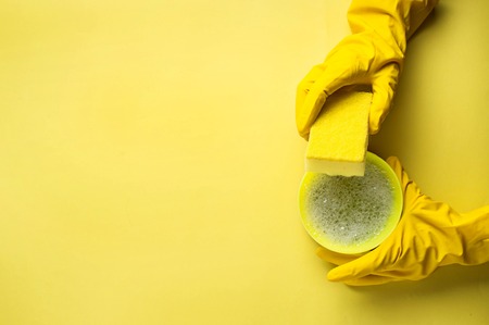Kitchen sponges and rubber gloves on yellow backgroundの写真素材