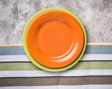 Empty orange and green plates on concrete tableの写真素材
