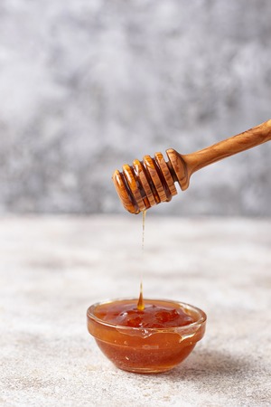 Honey dripping from a wooden dipper, close upの写真素材