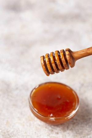Honey dripping from a wooden dipper, close upの写真素材