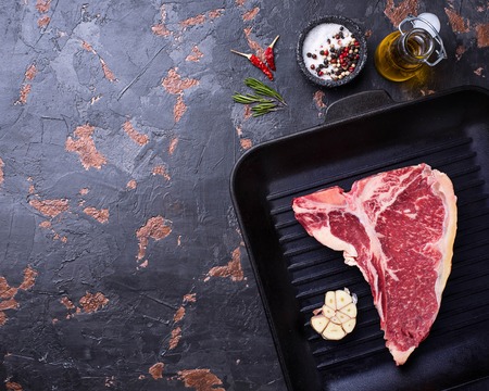 Raw T-bone steak on iron grill panの写真素材