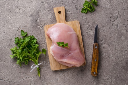 Uncooked chicken breast on cutting boardの写真素材
