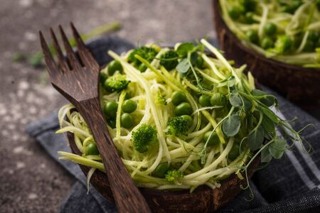 Zucchini pasta with green peas. Vegan dish in coconut bowlの写真素材