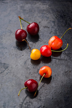 Fresh ripe red and yellow cherry on black background