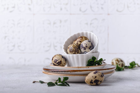 Bowl with quail eggs on light background