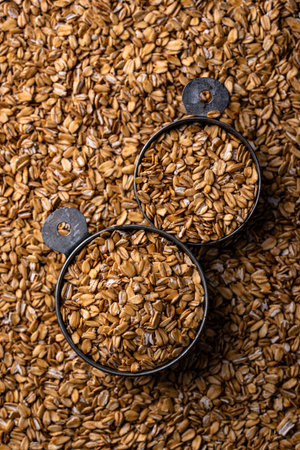 Texture of golden oats in metal measuring cups