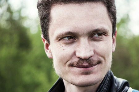 portrait of a young man with a mustache outdoors in springの写真素材