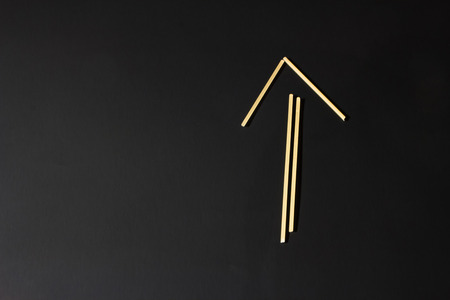 arrow pointing up is made of raw macaroni on a black backgroundの写真素材