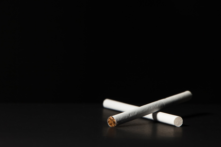 several thin white filter cigarettes on a black backgroundの写真素材