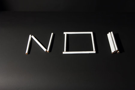 several thin white filter cigarettes on a black background