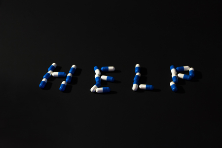 word help made of different pills on a black backgroundの写真素材