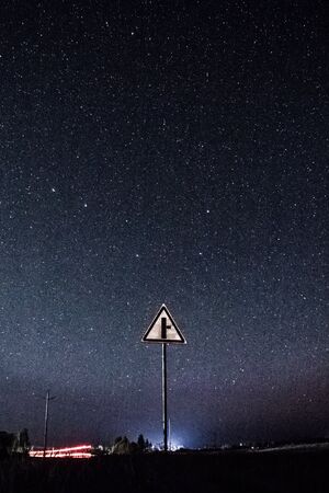 road sign in a field under a night sky full of starsの写真素材