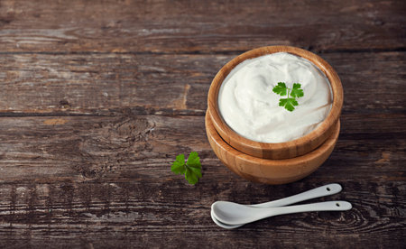 Sour cream in a bowl on wooden background