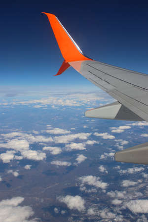 Photo from the plane window. White clouds and rocky mountains. From high. Under the wing of an airplaneの写真素材