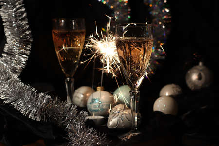 Two glasses of Champagne, bengal light and christmas decorations. Holiday atmosphere. Out of focus background. Merry Christmas and Happy New Year!の写真素材
