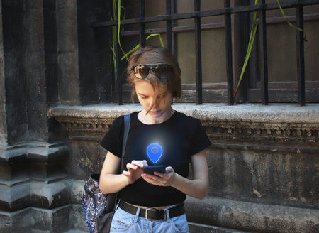 A young girl is looking for a location on a map in her phone. Excursion in the ancient city. Smoked...