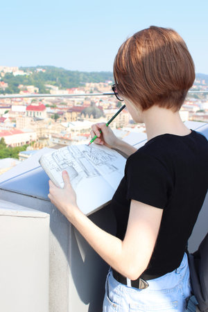 A young girl artist draws a sketch of the old city. Free tourism and travel until quarantine. Travel...