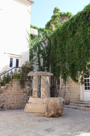 Italian style courtyard. White stones. Walls overgrown with plantsの写真素材