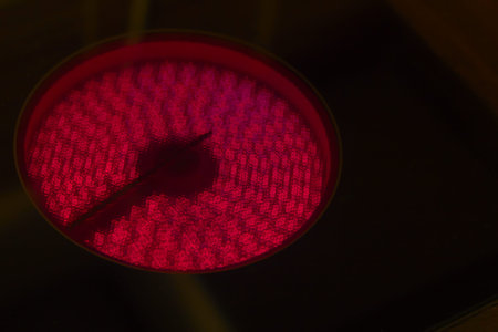Electric stove powered up, red hotplate glows red on black background
