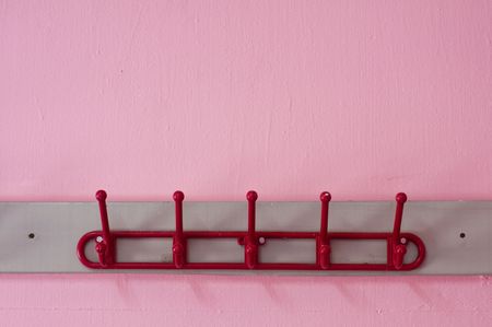 red coloured cloth hanger on a pink wallの写真素材