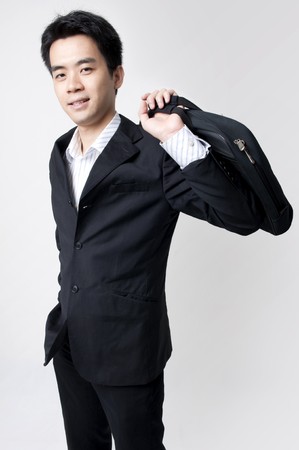 young male executive holding a business bag and smilingの写真素材