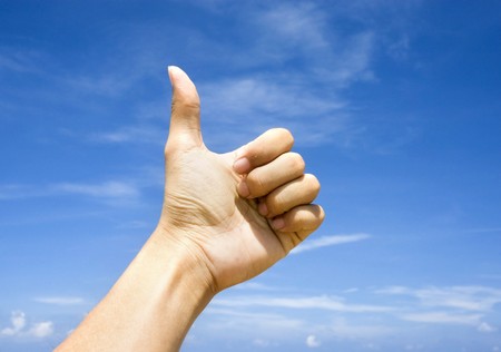 hand thumbs up with blue sky background の写真素材