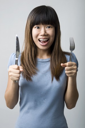 asian women on diet with fork and knifeの写真素材