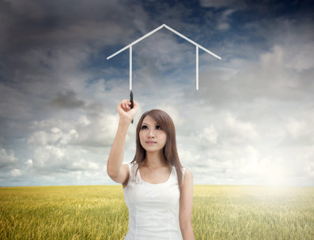 asian girl drawing a dream home during early morningの写真素材