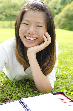 asian girl smiling and writing on outdoorの写真素材